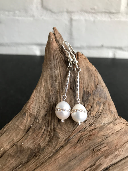 These Swarvorski drop pearl earrings with inlaid crystals are THE perfect finish to any outfit. Available in gold or silver, the 2 inch length will show off the large pearl with inlaid crystals.