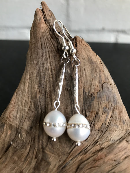 These Swarvorski drop pearl earrings with inlaid crystals are THE perfect finish to any outfit. Available in gold or silver, the 2 inch length will show off the large pearl with inlaid crystals.