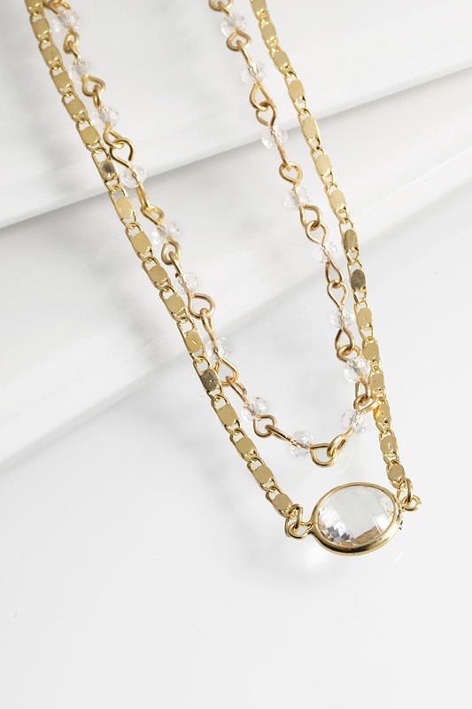 This delicate double layered bead necklace features a crystal charm and ﻿an interesting gold chain. It is 16" long with a 3" extender. Comes in Blush, Crystal, and Black.
